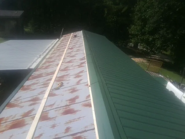 Old rusted panels beside newly installed green metal roofing — Wind Damage Roof Repair by Roofing Brothers in Blue Bell