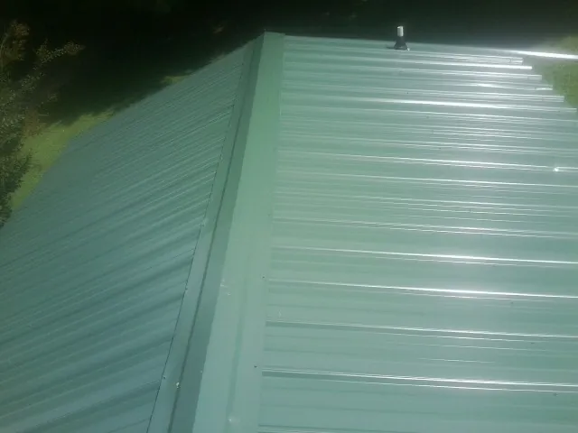 New green metal panels meeting at the ridge of a roof — Flat Roof Repair work by our crew in Blue Bell