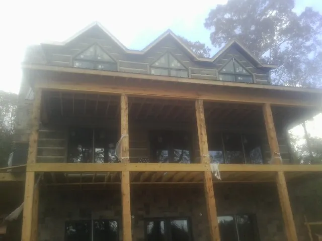 Dormers and porch framing on a large log home under construction — Roof Coating work by our crew in Blue Bell