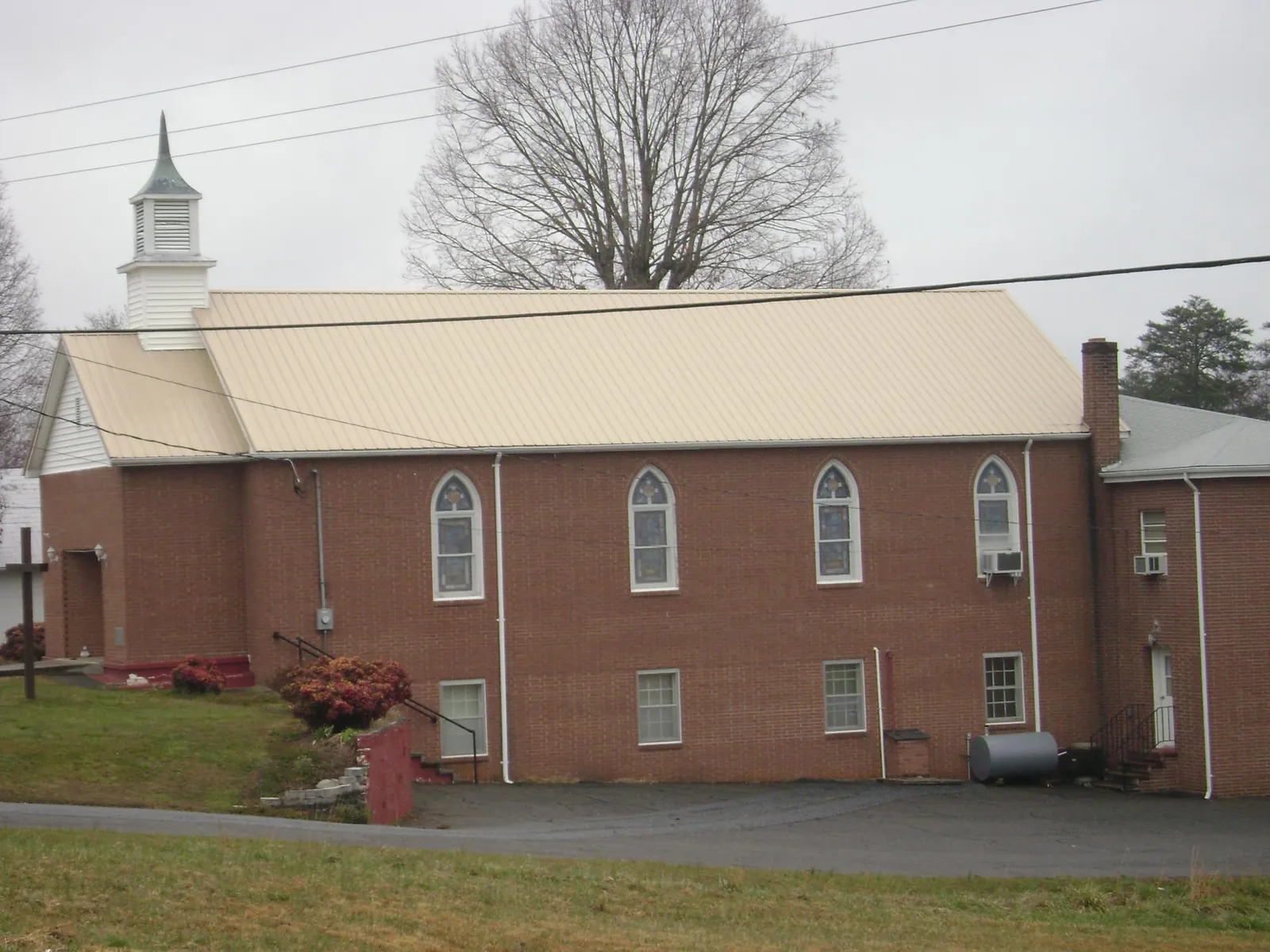 New tan metal roof on a brick church with a white steeple in Blue Bell