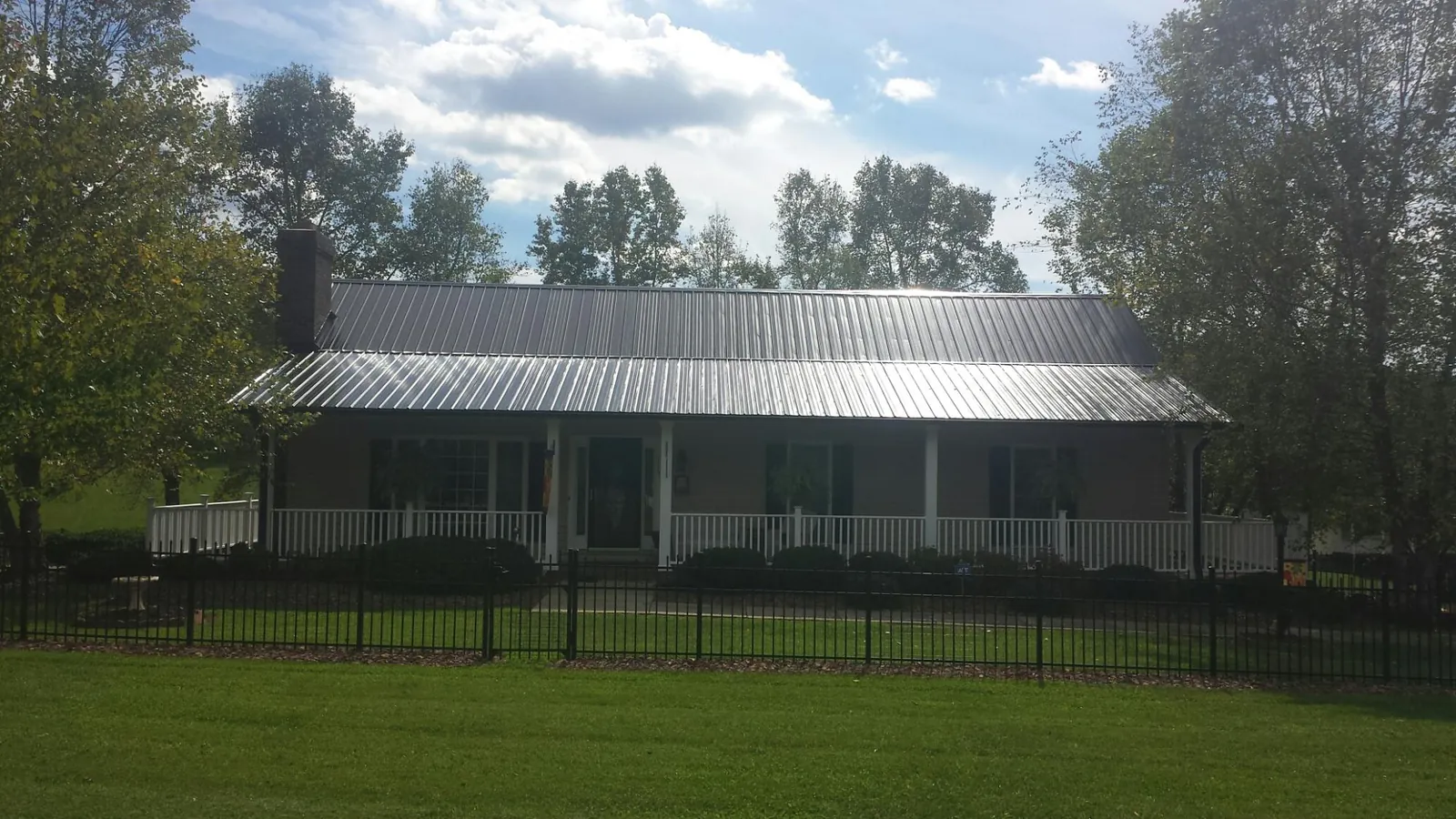 Gray metal roof on a brick ranch with a full width front porch — Gutter Guard Installation work by our crew in Blue Bell