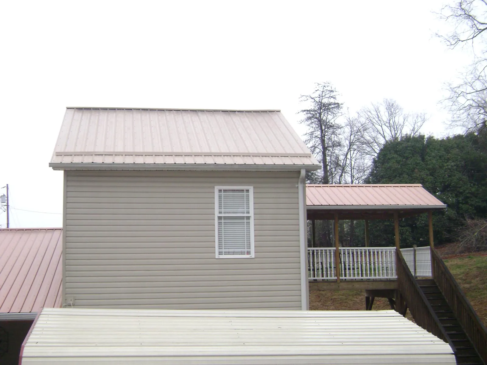 Tan metal roofs on a two story addition and attached porch, from a Roof Replacement job in Blue Bell