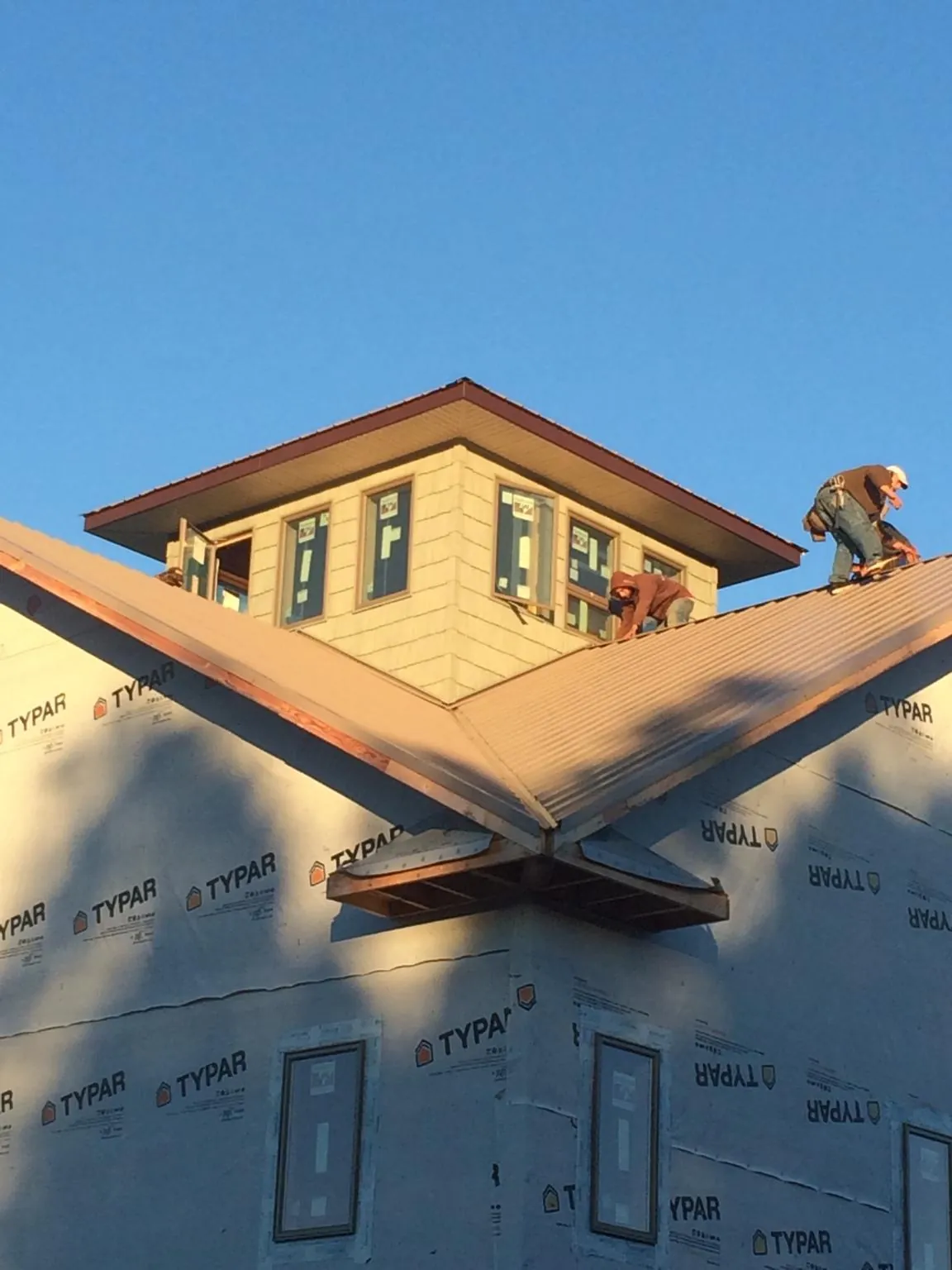 Roofers working around a rooftop cupola on a new metal roof at sunset — Roof Waterproofing in Blue Bell by Roofing Brothers